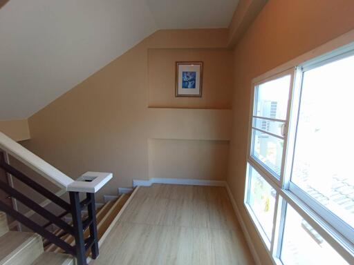 Bright staircase landing with large window and wooden floor