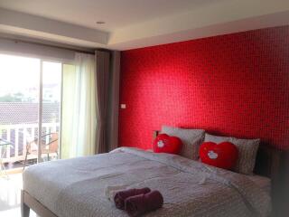 Spacious bedroom with large bed and red accent wall