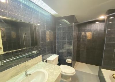 Spacious bathroom with modern fixtures and dark tiling