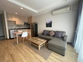 Modern living room with open kitchen design, hardwood flooring, and tastefully furnished