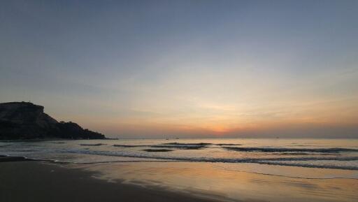 Serene beach sunset with gentle waves and clear skies