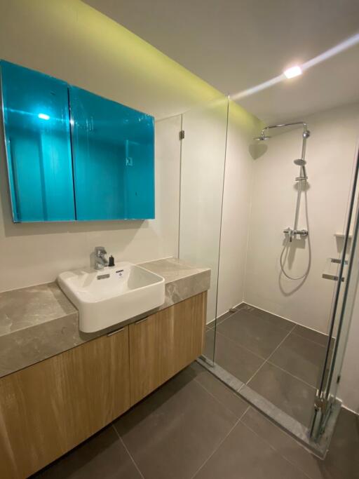 Modern bathroom with blue illuminated mirror and glass shower