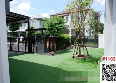 Modern house exterior with green lawn and gated entrance