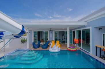 Bright outdoor pool area with waterslide and entertainment space