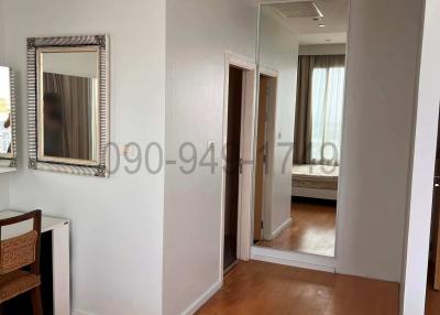 Brightly lit hallway with wooden flooring leading to bedroom