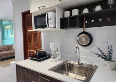 Modern kitchen interior with stainless steel sink, wooden cabinets, and open shelving