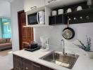 Modern kitchen interior with stainless steel sink, wooden cabinets, and open shelving