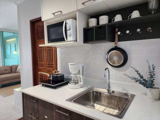 Modern kitchen interior with stainless steel sink, wooden cabinets, and open shelving