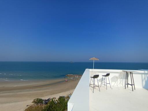 Oceanfront balcony with a panoramic view of the beach and clear blue sky