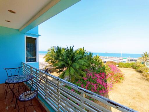 Spacious balcony with ocean view, seating area and tropical surroundings