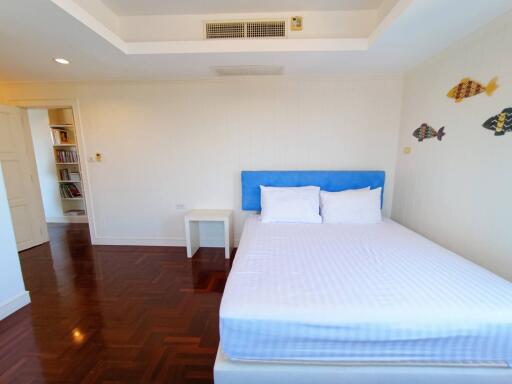 Spacious bedroom with a large bed, hardwood floors, and white walls