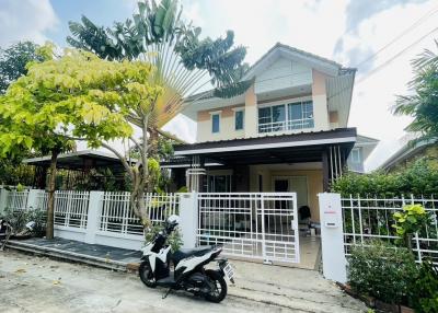 Two-story suburban house with a white fence and motorcycle parked in front