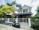 Two-story suburban house with a white fence and motorcycle parked in front