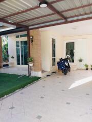 Covered patio area with tile flooring and a motorcycle parked