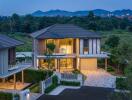 Modern two-story house exterior at dusk with illuminated interior, garage and beautiful mountain landscape in the background