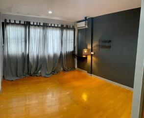 Spacious living room with hardwood floors and large curtains