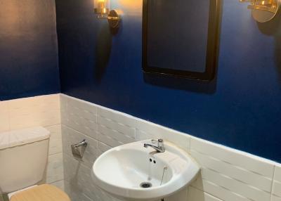 Modern bathroom with blue and white tiled walls, fancy light fixtures, and patterned floor