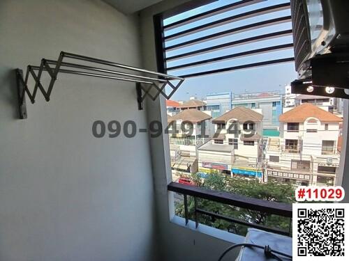 Compact balcony with a clothes drying rack overlooking the neighborhood
