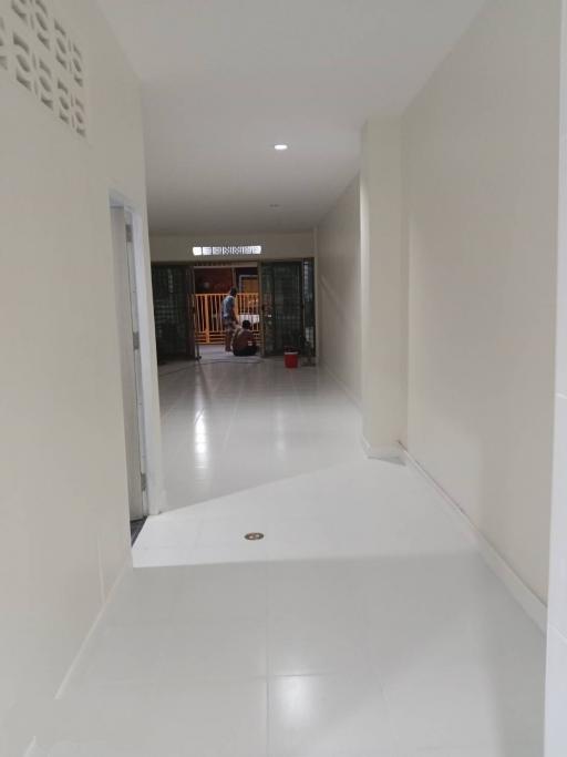 Bright and spacious white-tiled corridor leading to a gated entrance