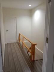 Brightly lit hallway with wooden railing and modern flooring