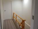 Brightly lit hallway with wooden railing and modern flooring