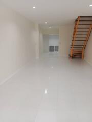 Spacious and bright unfurnished living area with glossy tiled flooring and staircase