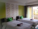 Bright and colorful twin bedroom with green accents and balcony access