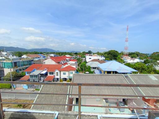 Panoramic view from a balcony showcasing a residential neighborhood with various rooftops and greenery under a clear blue sky
