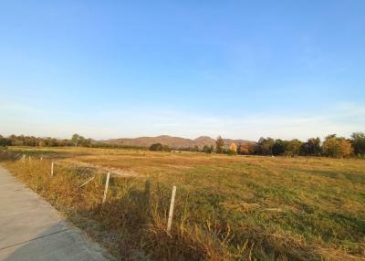 Expansive open field with mountain backdrop under clear sky