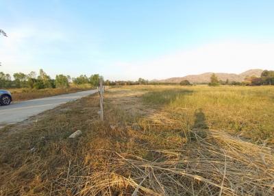Empty lot with dry grass alongside a road with scenic mountain background