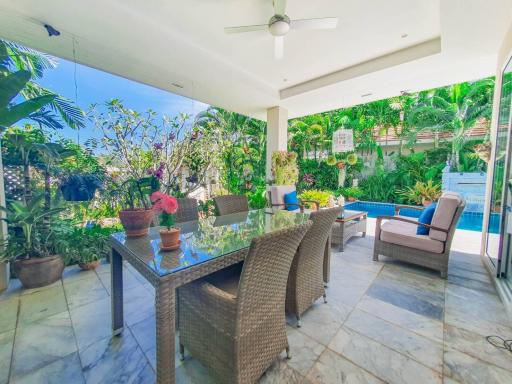 Spacious patio area with dining set, pool and lush greenery
