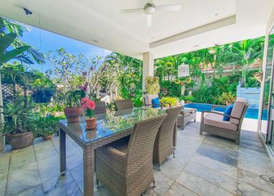 Spacious patio area with dining set, pool and lush greenery