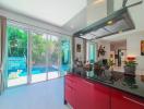 Modern kitchen with red cabinets, stainless steel appliances, and a view of the pool