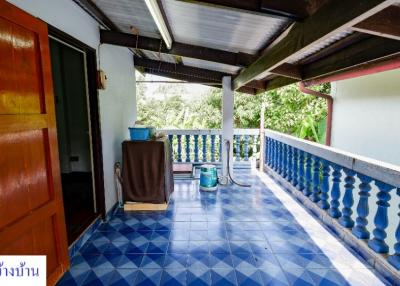 Spacious tiled balcony with blue patterned floor and railing, and views of the surrounding greenery