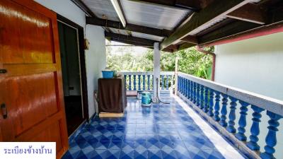 Spacious tiled balcony with blue patterned floor and railing, and views of the surrounding greenery