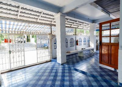 Covered patio area with blue tiled floor and white walls in a residential building