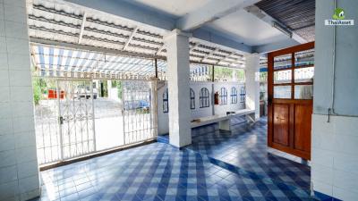 Covered patio area with blue tiled floor and white walls in a residential building