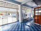 Covered patio area with blue tiled floor and white walls in a residential building