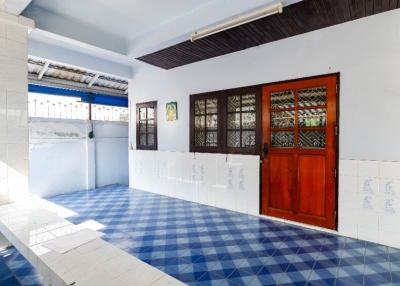 Spacious and brightly lit tiled room with red wooden door and white walls