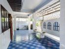 Bright and spacious covered veranda with blue patterned tiles and white columns