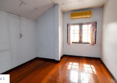Empty bedroom with wooden floor, window, and air conditioning unit