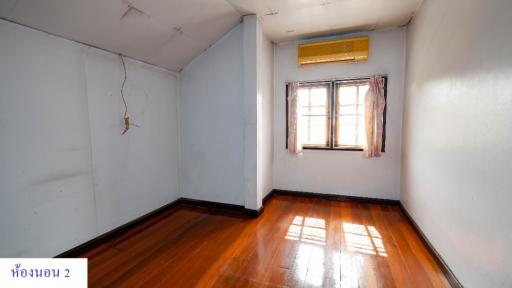 Empty bedroom with wooden floor, window, and air conditioning unit