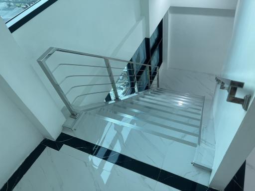 Modern staircase with chrome banisters and marble flooring