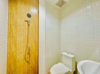 Modern bathroom with wall-mounted shower, white tiles, and wooden floor