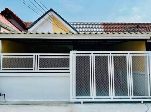 A front view of a residential house showing the gated entrance and the facade with a contrasting roof