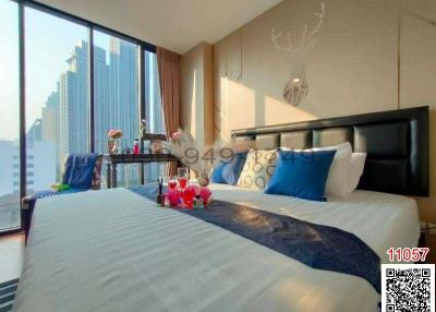 Modern bedroom with a large bed, city view, and decorative elements