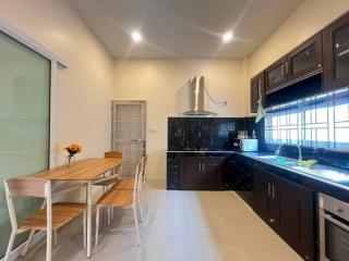 Modern kitchen with wooden dining table and dark cabinetry