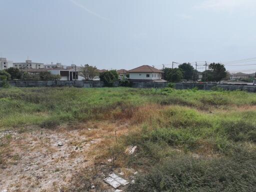 Exterior view of a residential area with a vacant lot and houses in the background under a clear sky