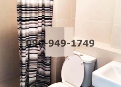 Compact bathroom with white ceramics and striped shower curtain