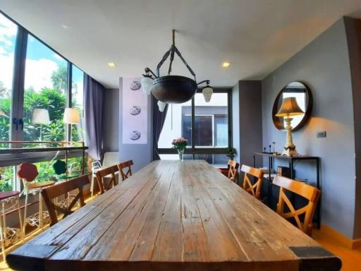 Spacious dining room with a large wooden table, modern chairs, and ample natural light